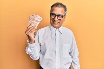 Wall Mural - Middle age indian man holding 50 turkish lira banknotes looking positive and happy standing and smiling with a confident smile showing teeth