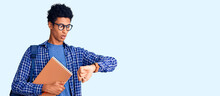 Young African American Man Wearing Student Backpack Holding Book Looking At The Watch Time Worried, Afraid Of Getting Late