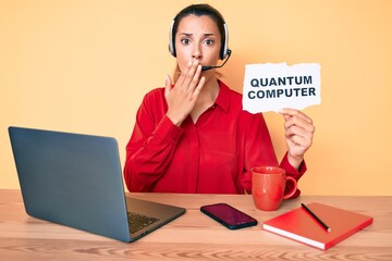 Wall Mural - Young brunette woman holding quantum computer banner covering mouth with hand, shocked and afraid for mistake. surprised expression