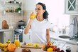 © My Ocean studio - Cute beautiful and happy young brunette woman in the kitchen at home is preparing fruit vegan salad or a healthy smoothie and having fun