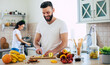 © My Ocean studio - Excited happy beautiful young couple in love cooking in the kitchen and having fun together while making fresh healthy fruits salad