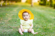© Any Grant - a little girl of 8 months is sitting in the summer on the green grass in a yellow summer dress and hat, a place for text