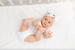 © Any Grant - happy baby is lying in a crib in the children's room on a white bed