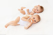 © Any Grant - twin babies boy and girl with a bottle of milk on a white bed at home, baby food concept, place for text