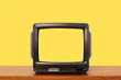 © Pituk - Yellow color background, vintage old television on wood table with blank yellow screen.