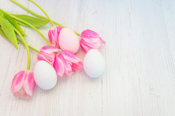 Wall Mural - Happy Easter holiday greeting card. Bouquet of pink tulips and easter eggs on white wooden background. Space for text