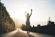 © BullRun - Back view of happy caucasian slim woman in casual wear raising hands feeling free and overjoyed with summer vacations, positing young female walking near ocean and breathtaking natural landscape