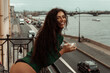 © Dashskala - cheerful brunette with beautiful smile on the balcony with a coffee cup looking at the city life and neva river in saint petersburg