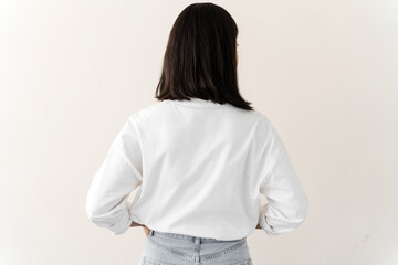millennial female wearing white t-shirt standing turning back to camera. young woman standing isolat