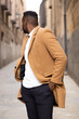 © PEDROMERINO - Handsome and stylish african american walking and looking back on a street.