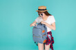 Beautiful portrait young asian woman wear sunglasses and hat open backpack and surprise travel summer trip holiday in vacation isolated on blue background, tourist girl excited and shocked having bag.