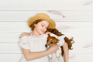 Little girl embracing her dog lying on a wooden floor.