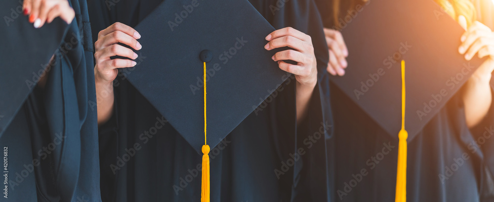 Close up group of graduates holding a hat At the graduation ceremony at the university - obrazy, fototapety, plakaty 