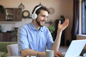 Sticker - Happy young man in earphones working on laptop from home during self isolation.