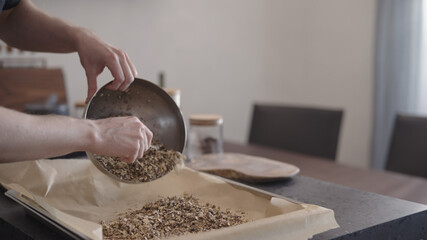 Wall Mural - man making granola pour it on baking tray with parchment paper