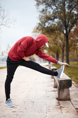 Wall Mural - Athletic sporty man training in hoodie sweatshirt in urban city park.