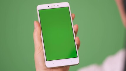 Phone in the hand close up isolated at green background. Phone screen is green chroma key, background chroma key green screen