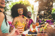 © Davide Angelini - Multiracial group of friends having fun at backyard home party - Young people laughing together drinking cocktails at bar restaurant - Focus on black woman