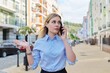 © Valerii Honcharuk - Young serious business woman talking on mobile phone, city street background