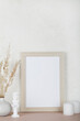 © Анна Мартьянова - Portrait empty wooden frame mockup, dried pampas grass, small statue and candles on white background, interior, home design. Art concept. copy space.