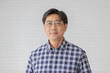 © Bangkok Click Studio - Portrait close up shot of middle aged asian male model with short black hair wearing blue plaid shirt with stand smiling in front of white background