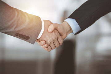 Business people standing and shaking hands in sunny office, close-up. Handshake and marketing