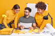 © WHstudio Leushin N - Three multicutural people colleagues work together on architectureal project collaborate at desktop with papers and blueprints brainstorming on working session isolated over yellow background