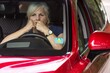 Scared elderly woman looks with horror through the window of a red car