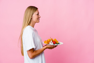 Wall Mural - Young russian woman eating a waffle isolated gazing left, sideways pose.