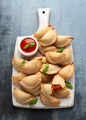 Wall Mural - Margarita Margherita pizza parcels pockets filled with tomato, mozzarella cheese and basil served on white wooden board. Party finger food