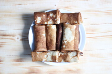 Wall Mural - Stuffed panckakes on plate on wooden background for Maslenitsa