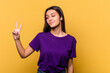 © Asier - Young Indian woman isolated on yellow background joyful and carefree showing a peace symbol with fingers.