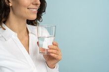 Close Up Of Caucasian Woman Wear White Blouse Holding Drinking Water Glass In Her Hand, Isolated On Studio Blue Background. Healthy Lifestyle, Health Care Treatment Concept. 
