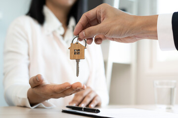 Wall Mural - A new homeowner accepts a house key from a real estate agent after agreeing to a successful buy-home purchase-sale contract. House selling concept