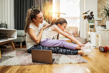 Beautiful young mother practicing fitness exercising and yoga together with her adorable little son. They are enjoying, playing and smiling.