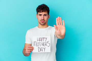 Wall Mural - Young caucasian man holding a happy mothers day placard isolated standing with outstretched hand showing stop sign, preventing you.