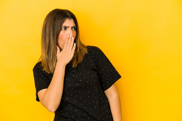 Wall Mural - Young indian woman isolated on yellow background being shocked because of something she has seen.