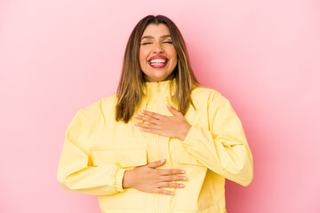 Wall Mural - Young indian woman isolated on pink background laughs happily and has fun keeping hands on stomach.