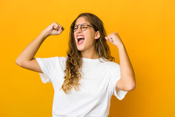 Young caucasian woman raising fist after a victory, winner concept.