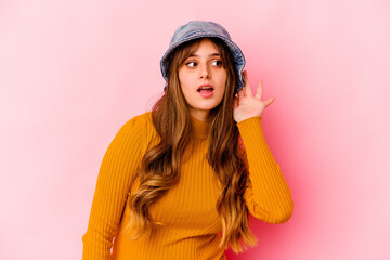 Wall Mural - Young caucasian woman wearing fishermans hat isolated trying to listening a gossip.