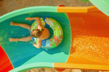 Wall Mural - Summer holiday concept. Top view of cute little child girl having fun outdoors in aqua park. Horizontal image.