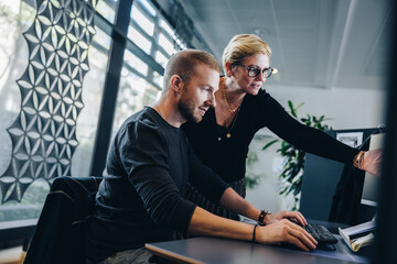 Manager assisting colleague working in office