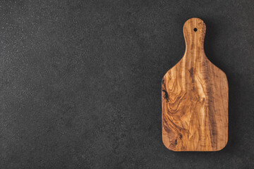 Empty olive wood kitchen board on black table. Top view.