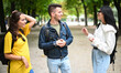 © Minerva Studio - Three students talking to each other outdoor in a college courtyard