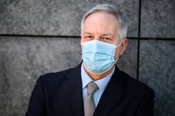 Wall Mural - Mature business man portrait outdoor wearing a protective mask against covid 19 coronavirus pandemic