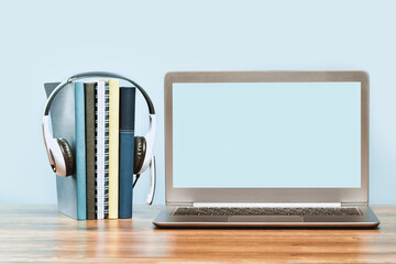 Wall Mural - Laptop. Mockup screen and headphones on wooden desk and plain background banner. Distant learning. working from home, online courses or support minimal concept. Notepads with headset