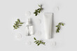 Bottles of serum with green leaves flat lay on white background