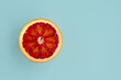 One slice of red oranges on a trendy blue background. Top view and copy space