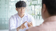 © Puwasit Inyavileart - Young Asian man in a white robe talks to a man, Doctors diagnose diseases and give advice or treatment solutions to patients in the hospital examination room, Explaining medical examination results.