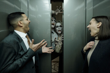 Young contemporary thrilled office managers in formalwear shouting in horror in moving elevator